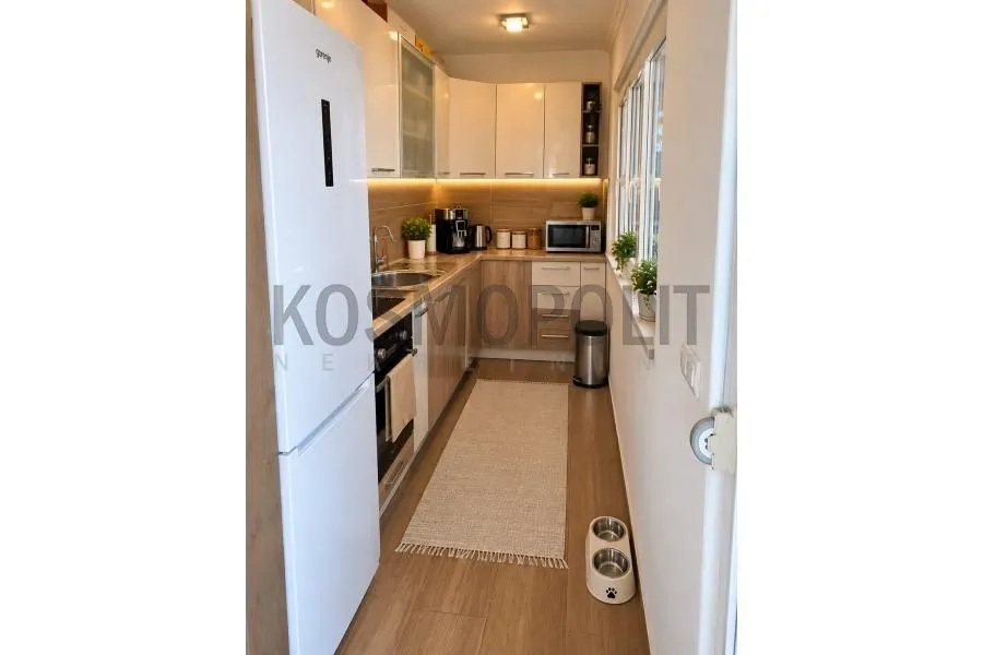Small narrow kitchen with a white refrigerator and wooden cabinetry.