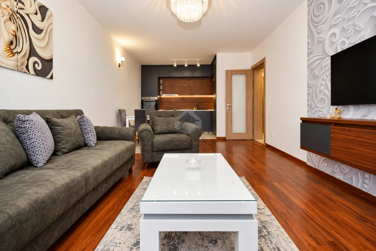 Living room with sofa, coffee table and TV, connected to the kitchen.