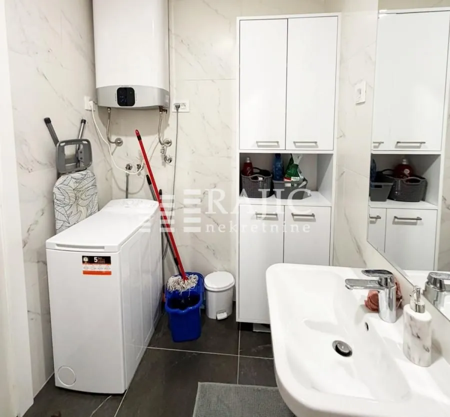 Small bathroom with a washing machine, sink, and white cabinet.