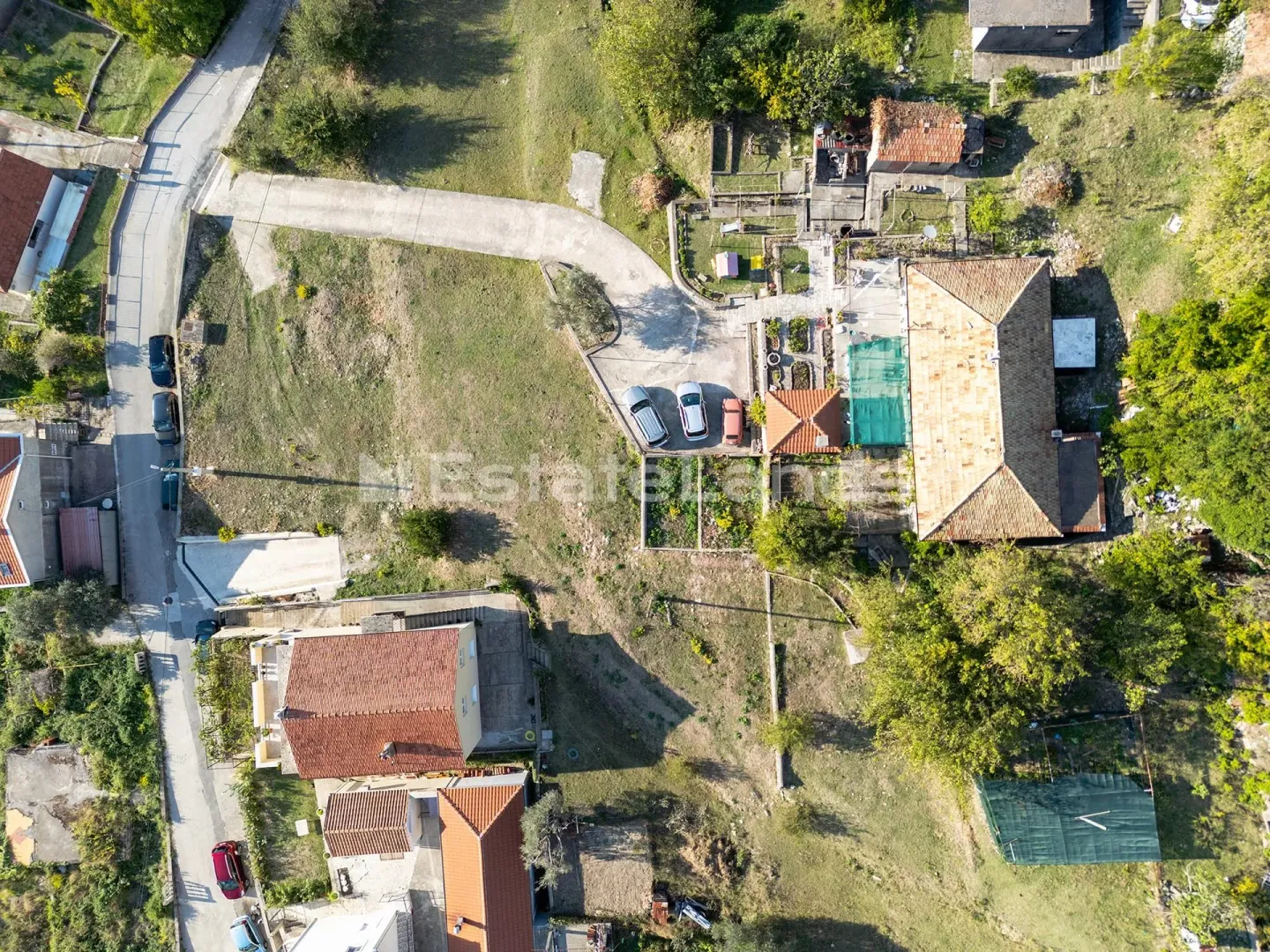 Pogled iz vazduha na imanje sa kućom, dvorištem i pristupnim putem.