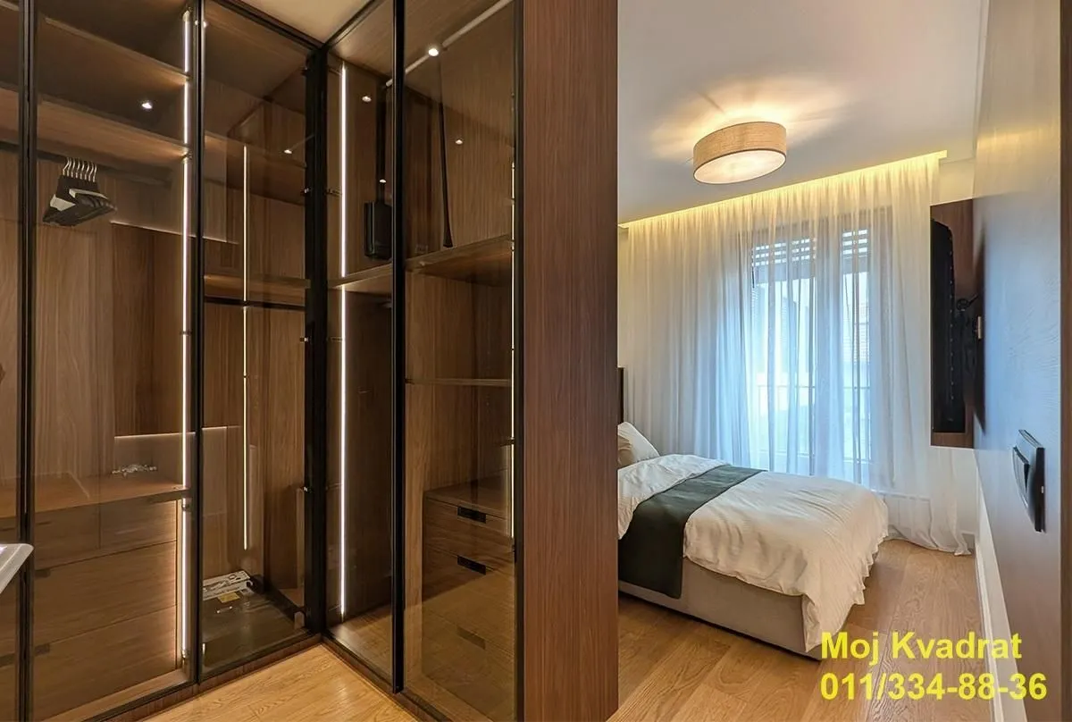 Modern bedroom with a walk-in wardrobe with glass doors.