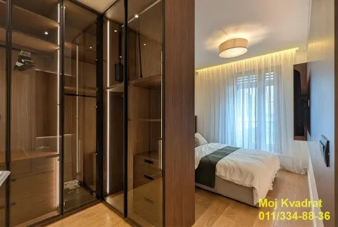 Modern bedroom with a walk-in wardrobe with glass doors. - image 8