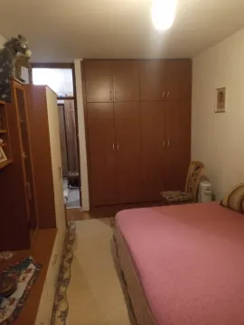 Spavaća soba sa velikim drvenim ormarom i krevetom sa roze prekrivačem. - image 7