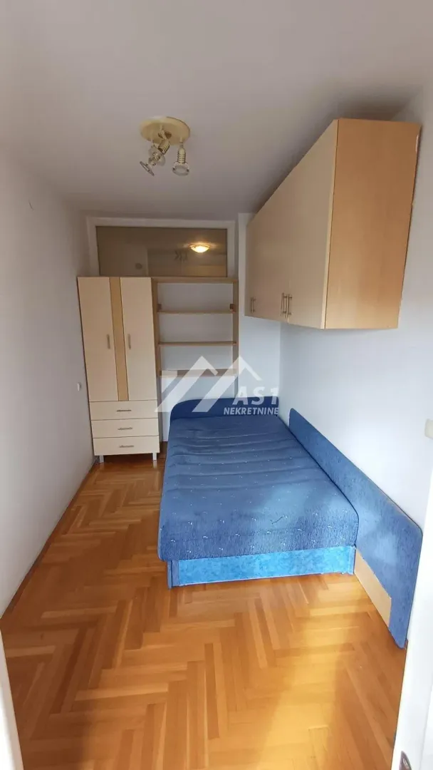 Small bedroom with a bed, wardrobe, and wall-mounted cabinets.