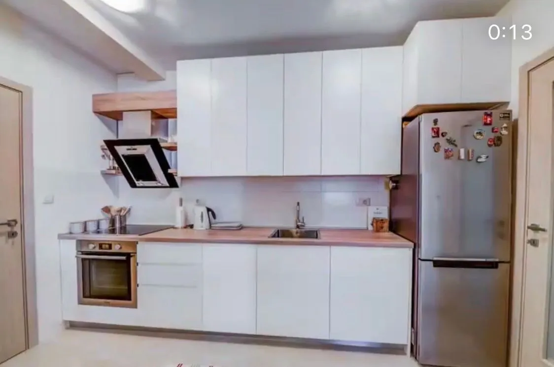 Modern white kitchen with built-in appliances and a refrigerator.