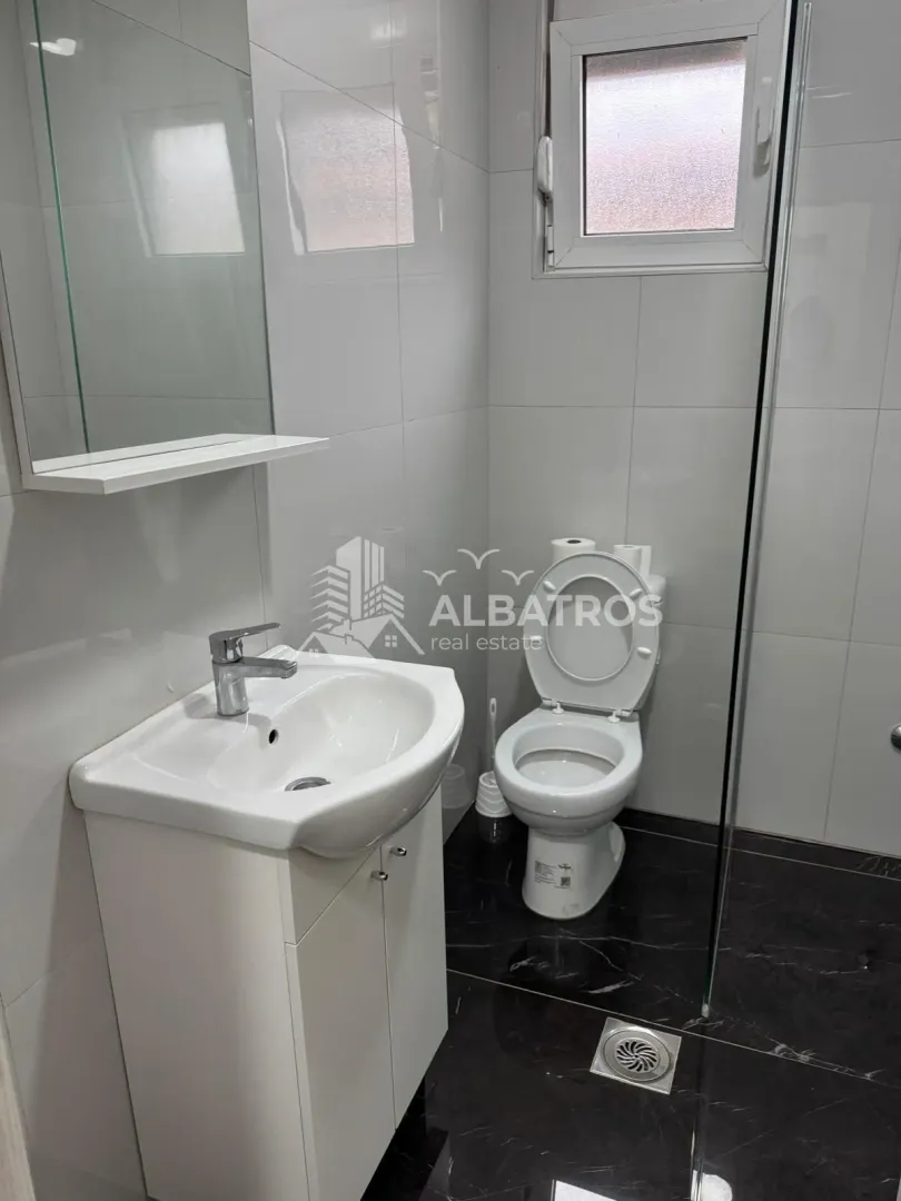 Smaller bathroom with white tiles, washbasin and toilet.