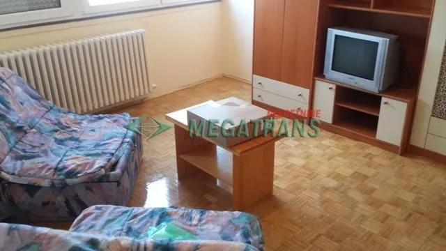 Manji dnevni boravak sa garniturom za sedenje i drvenim nameštajem.