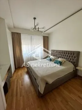 Nameštena spavaća soba sa bračnim krevetom, drvenim podom i prozorom sa zavesama. - image 5