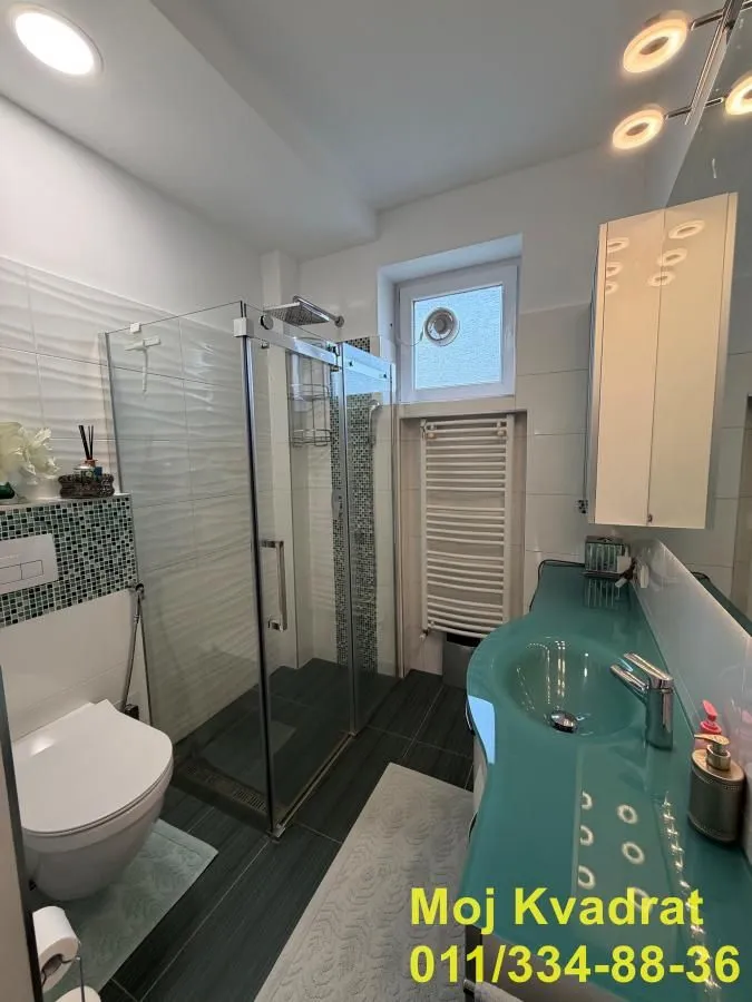 Modern bathroom with a shower cabin, toilet, and sink.