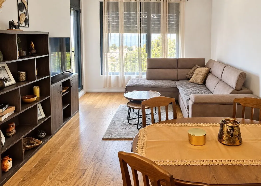 Spacious living room with a sofa, TV and dining table.