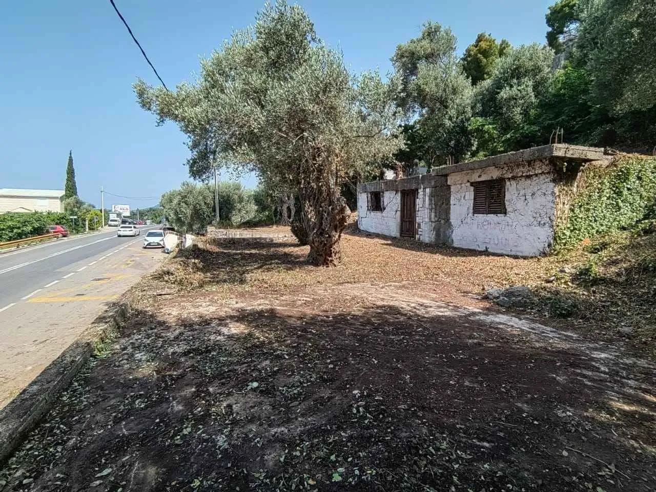 Pogled na stari objekat i dvorište pored puta.