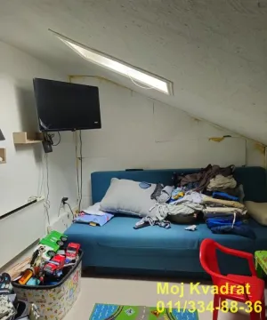 Potkrovlje sa plavom garniturom i televizorom na zidu. - image 14
