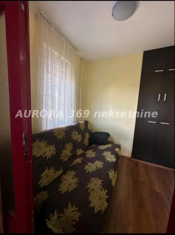 Manja spavaća soba sa kaučem i ugradnim ormarom.