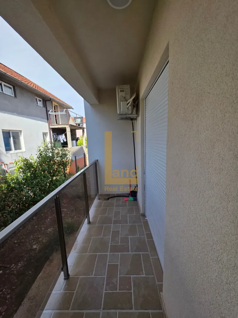 Covered balcony with tiled flooring and a glass railing.