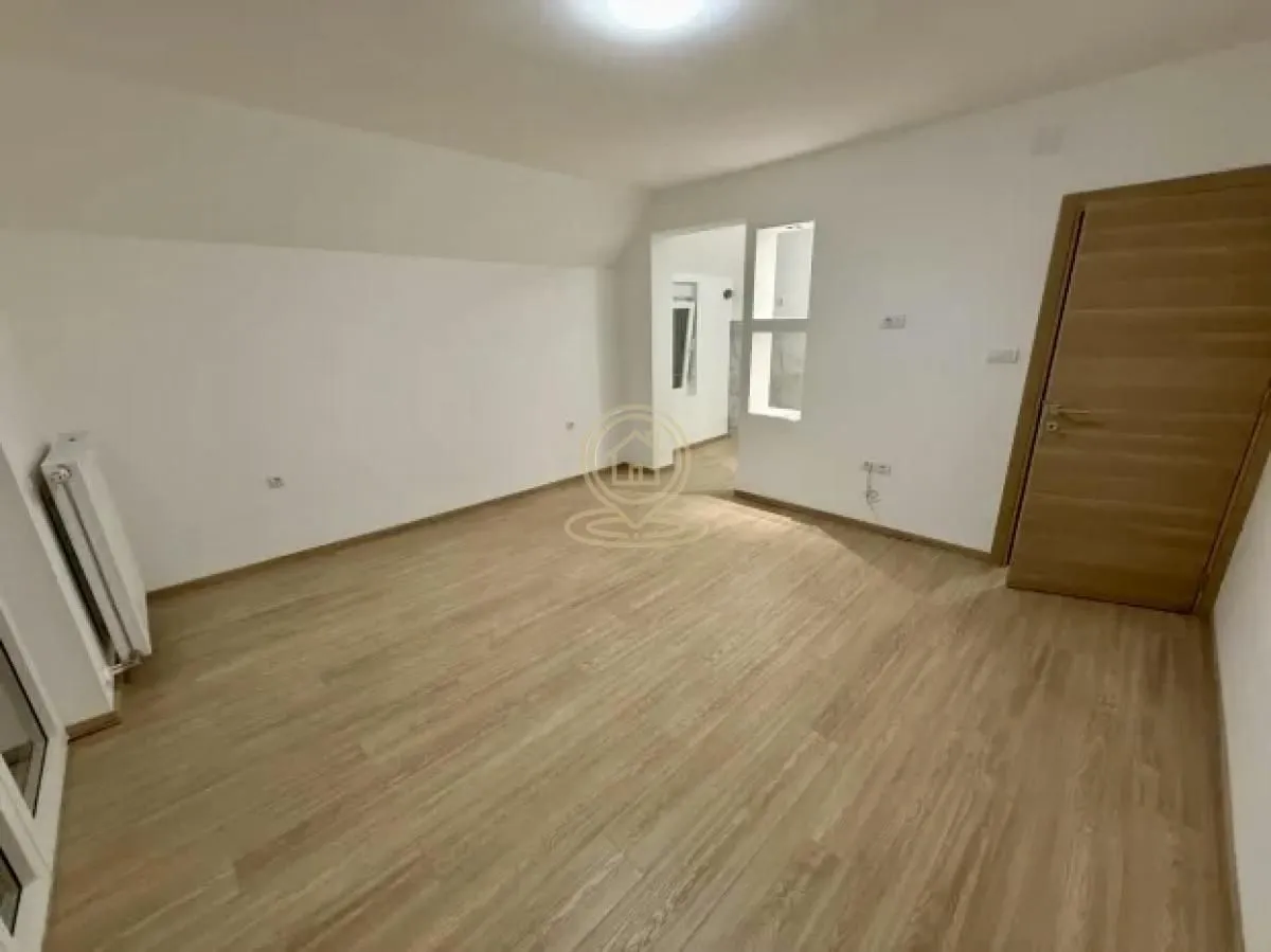 Prazna soba sa laminatom i drvenim vratima.