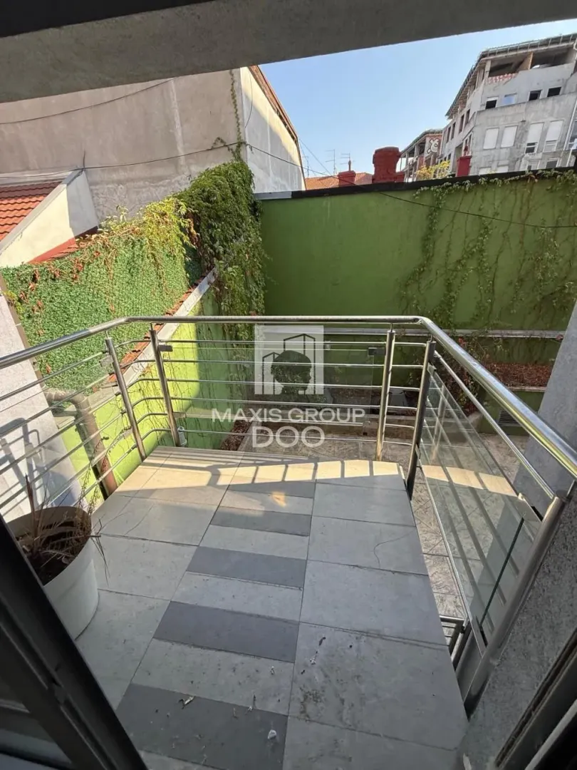 Small tiled balcony with metal railing and a view of the courtyard and surrounding buildings.