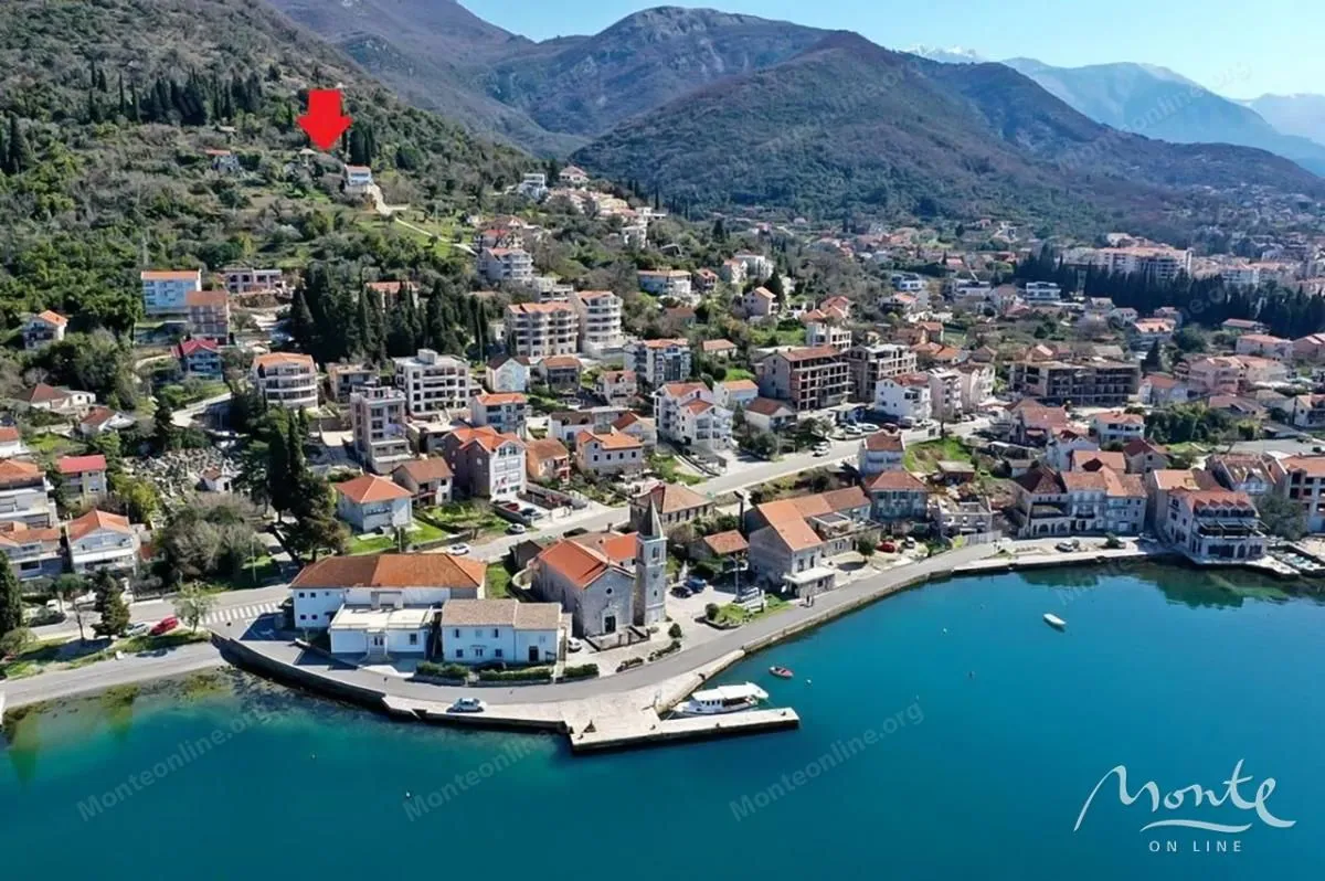 Pogled iz vazduha na obalu sa naseljem i planinskim okruženjem.