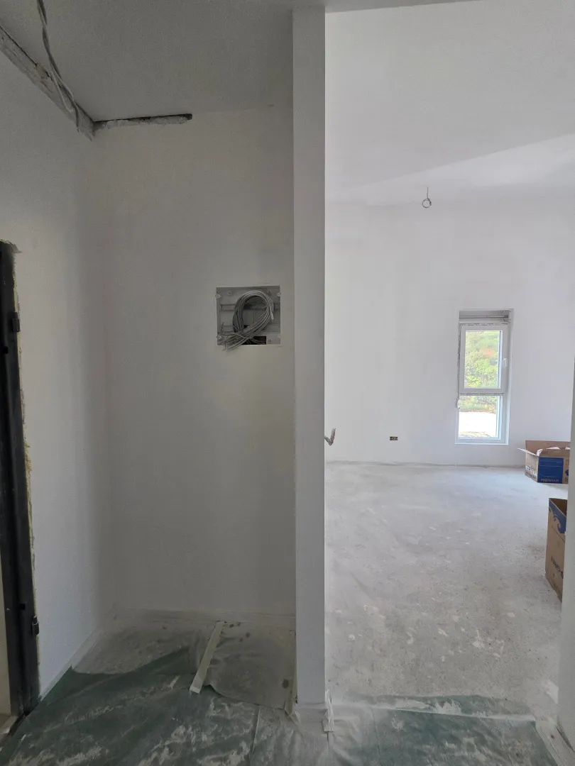 Unutrašnjost nenamještenog stana u izgradnji sa bijelim zidovima i prozorom.