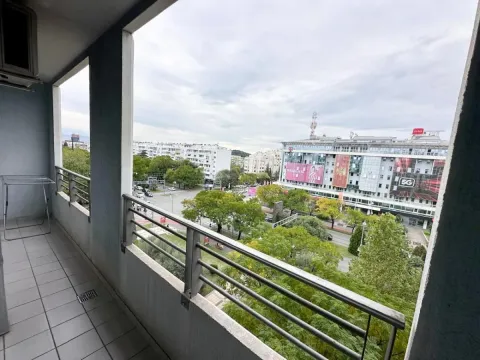 Dugačak natkriveni balkon sa metalnom ogradom i pogledom na gradsku ulicu i zgrade. - image 9