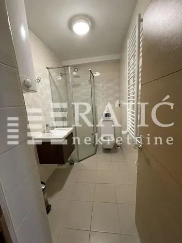 Modern bathroom with a shower cabin, washbasin, and toilet.