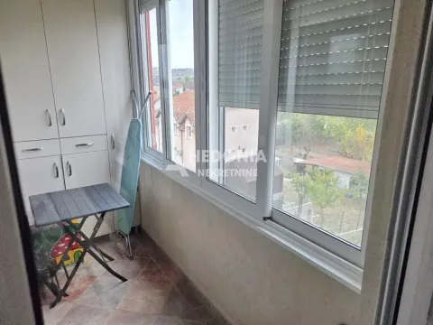 Zastakljeni balkon sa ugradnim ormarom i pogledom na naselje. - image 2