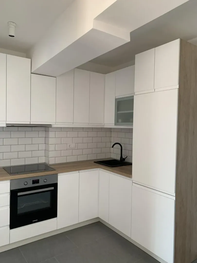 Modern white kitchen with a wooden countertop and built-in appliances.