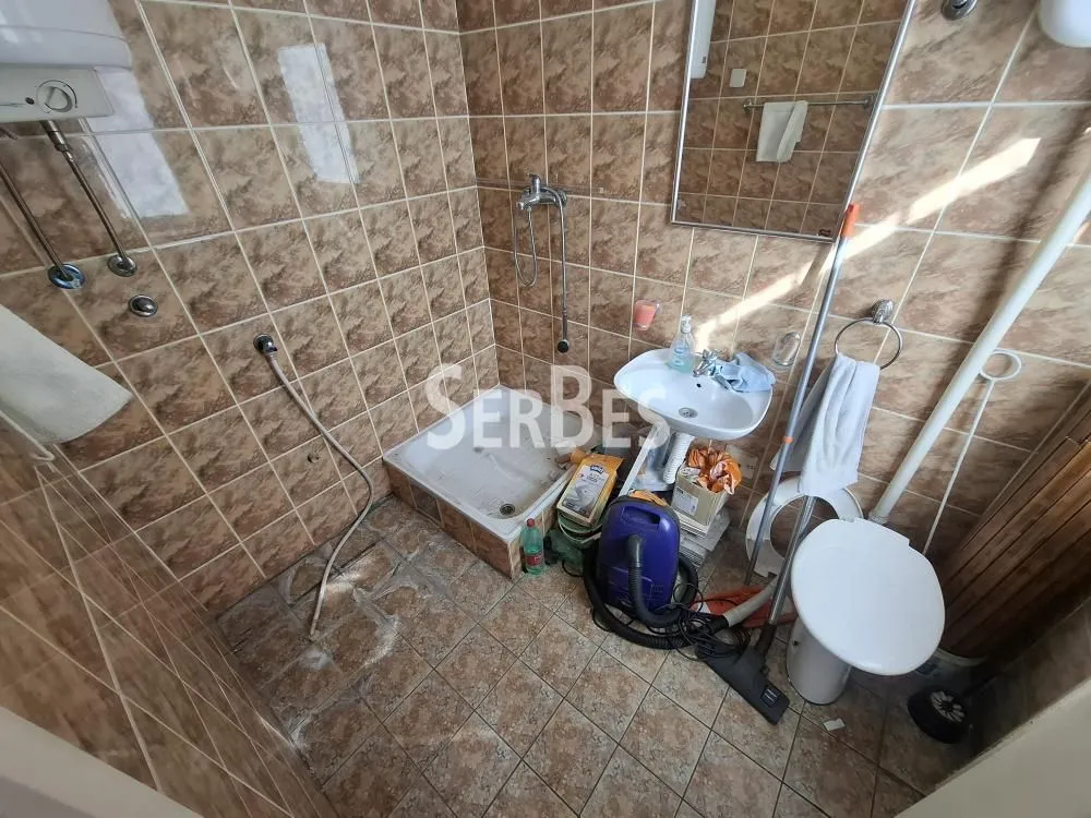 Manje kupatilo obloženo keramičkim pločicama sa tuš kabinom i sanitarijama.