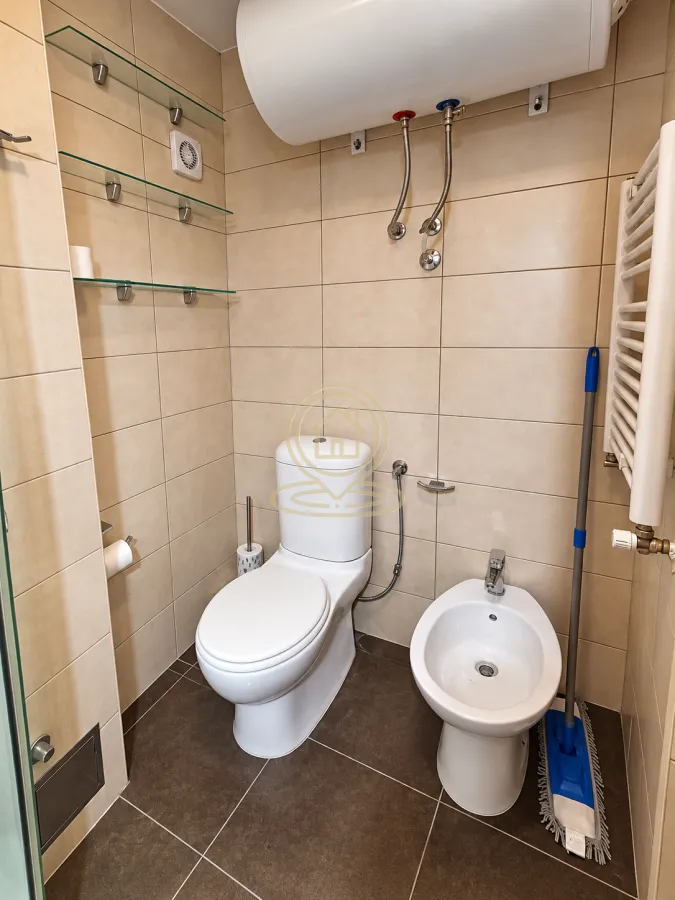 Compact bathroom with a toilet, bidet, and water heater.