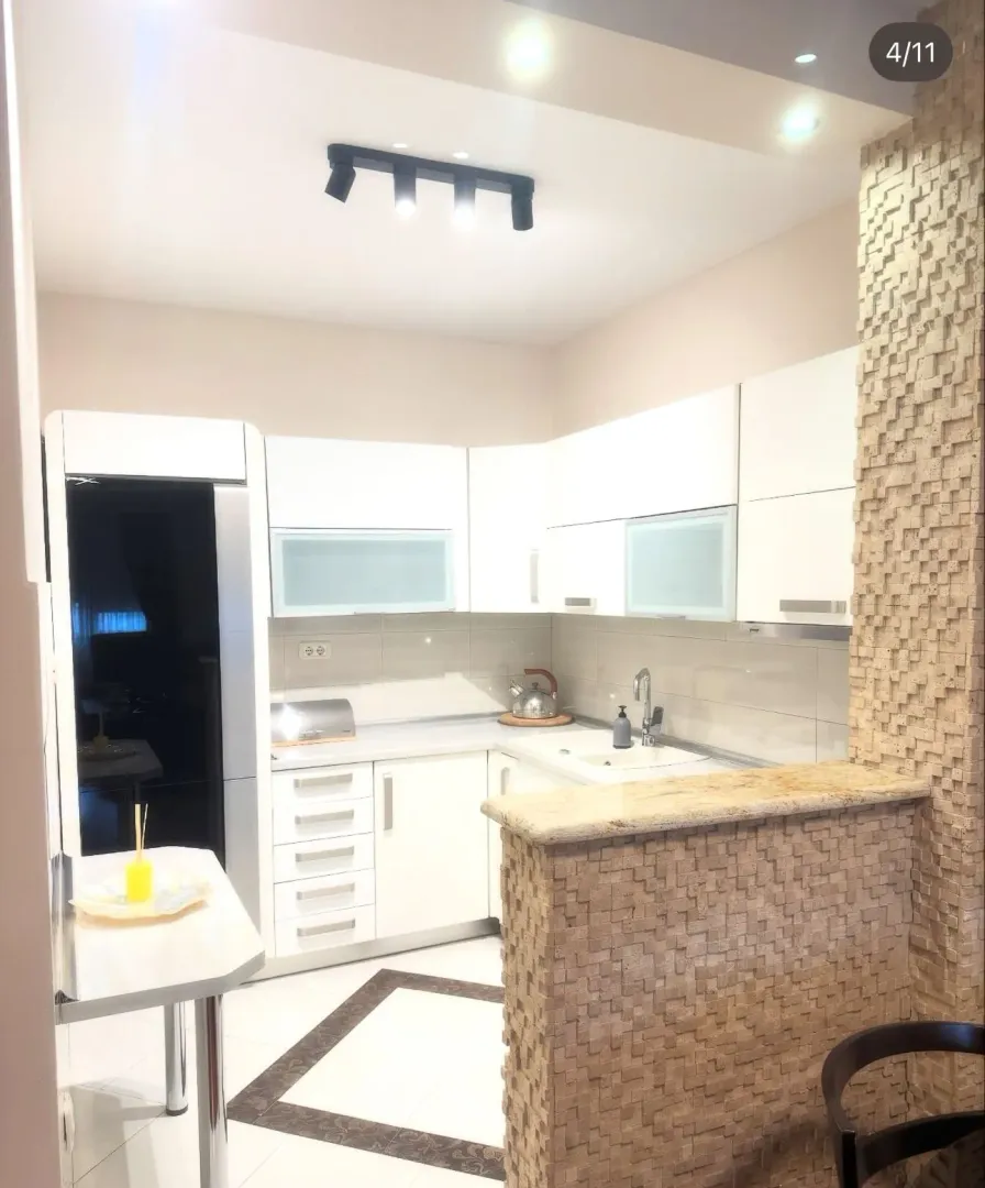 Modern kitchen with white cabinetry and decorative stone details.