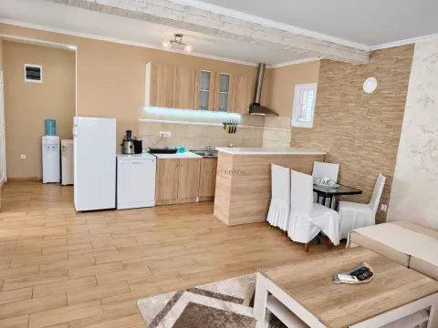 Open-plan kitchen with wooden cabinetry, a breakfast bar, and a dining table. - image 7