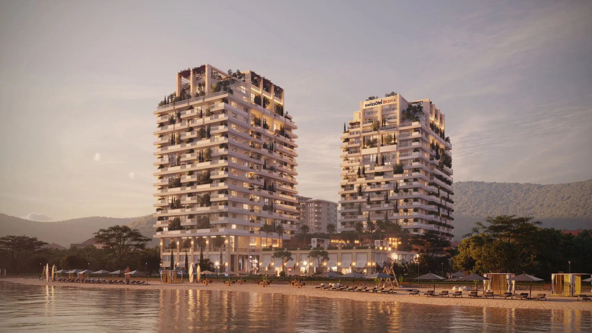 Pogled sa plaže na moderan stambeni kompleks sa hotelom u sumrak.