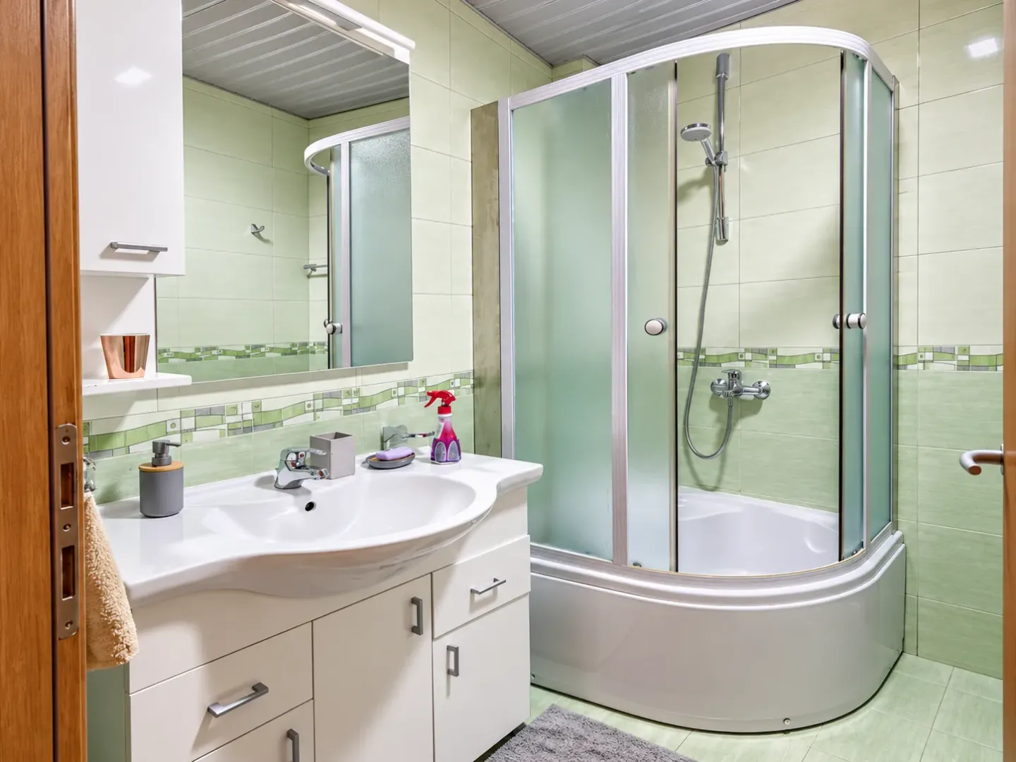 Brightly decorated bathroom with a sink, mirror, and shower cabin.