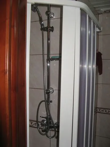 A shower cabin in a bathroom with ceramic tiles.