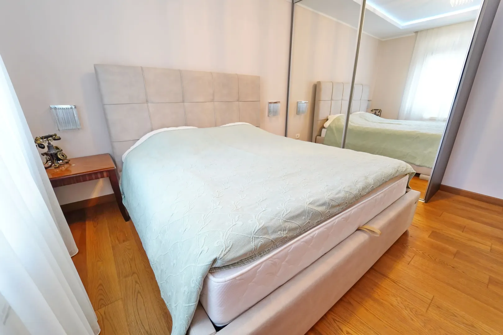 Furnished bedroom with a double bed and a large mirrored wardrobe.