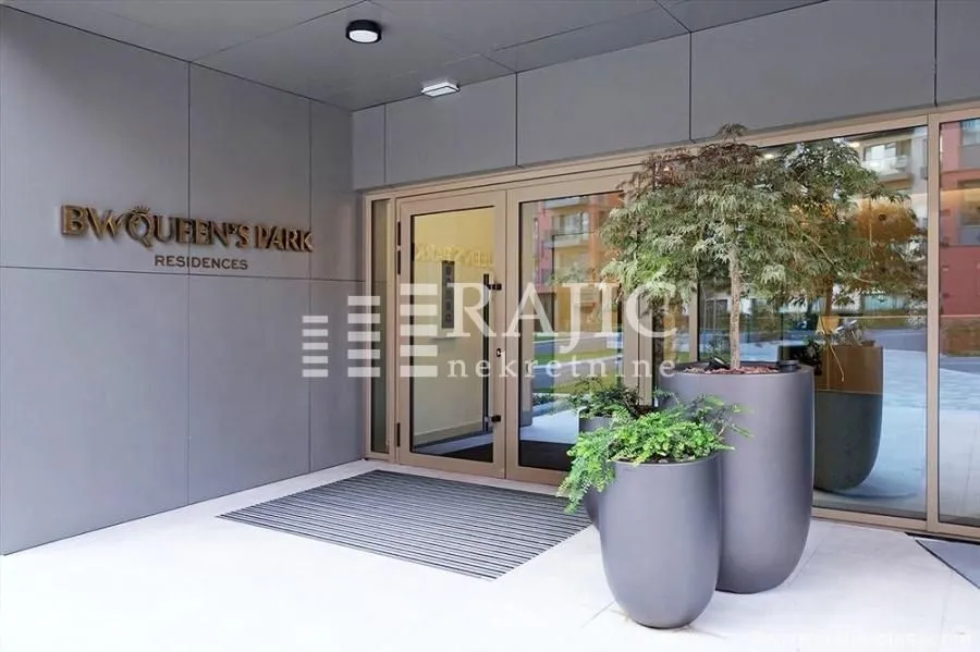 Entrance to a residential building with a modern facade and potted plants.