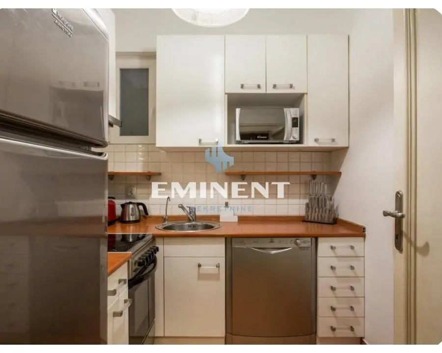 Compact equipped kitchen with white cabinetry and household appliances.