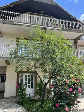 Yard with trees and house facade with a balcony. - image 3