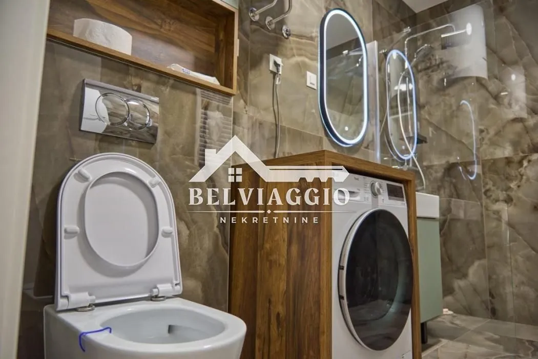 Modern equipped bathroom with a walk-in shower, wall-hung toilet, and washing machine.