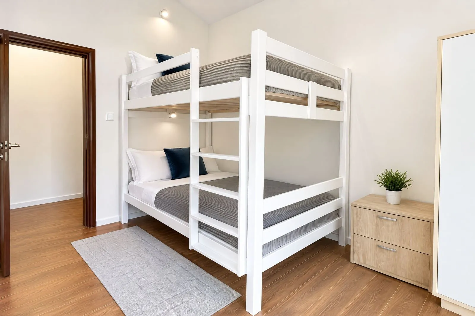 Bright bedroom with a white bunk bed and wooden flooring.