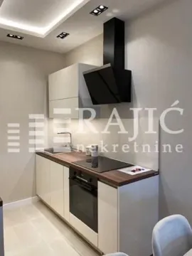 Modern kitchen with white cabinets, dark countertop, and built-in appliances. - image 13