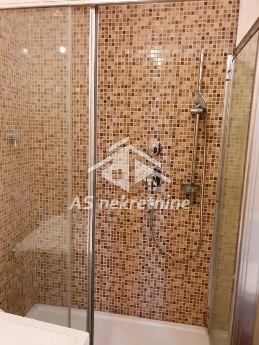 Walk-in shower enclosure with mosaic tiles and glass screen.