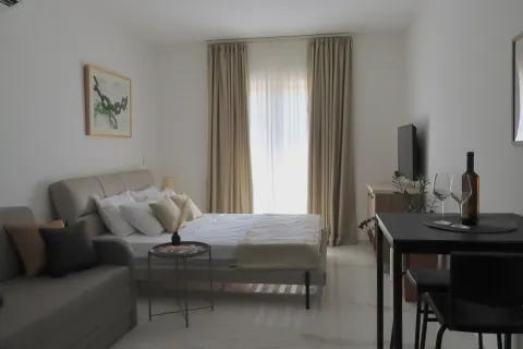 Furnished bedroom with a double bed, sofa, TV, and dining table. - image 2