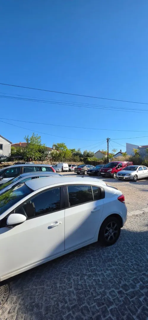Parking prostor sa parkiranim automobilima ispred objekta.