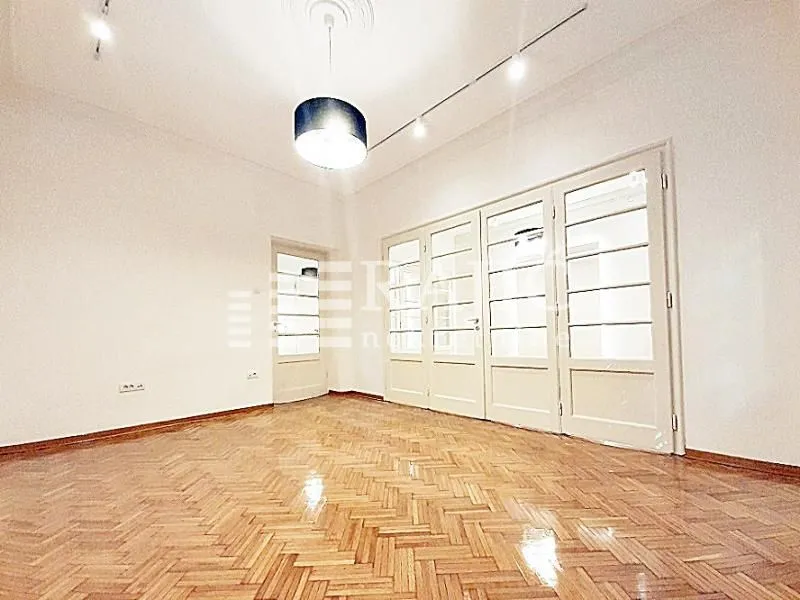 Empty room with parquet flooring and white double doors.