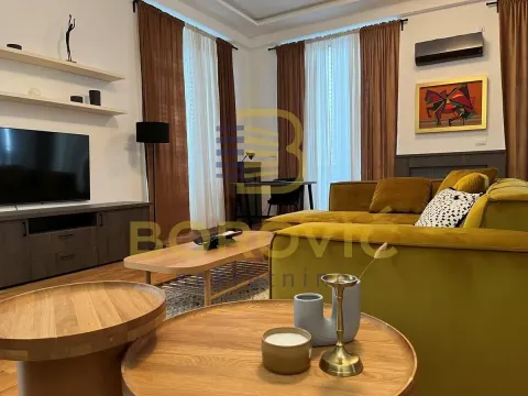 Living room with a sofa, TV, and wooden coffee tables. - image 4