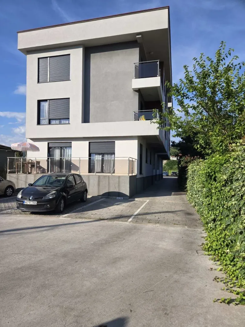 Exterior of a modern residential building with a parking space in front.