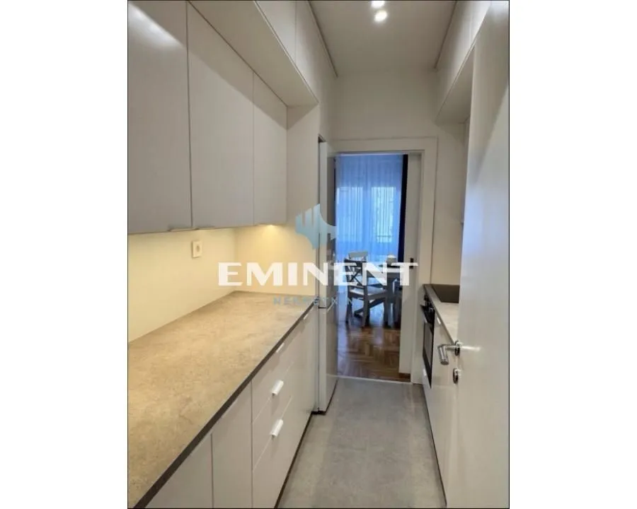 Narrow kitchen with white cabinetry and a wood-patterned countertop.