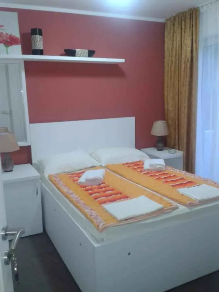Namještena spavaća soba sa bračnim krevetom i noćnim stočićima.