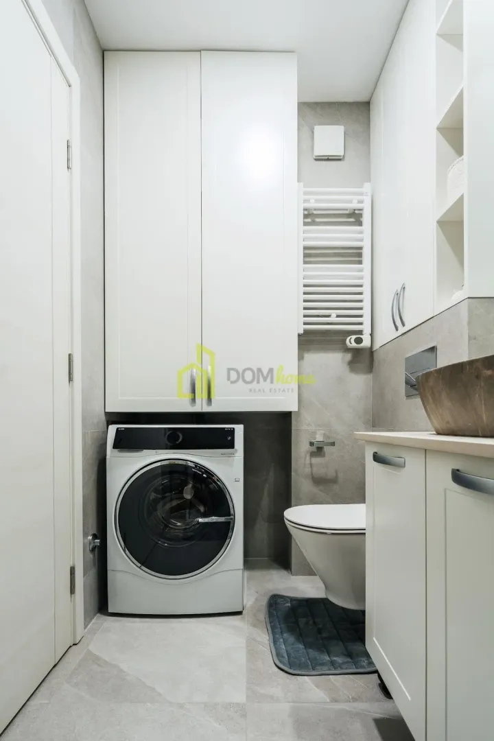 Modern bathroom with a washing machine, built-in cabinetry, and a toilet.