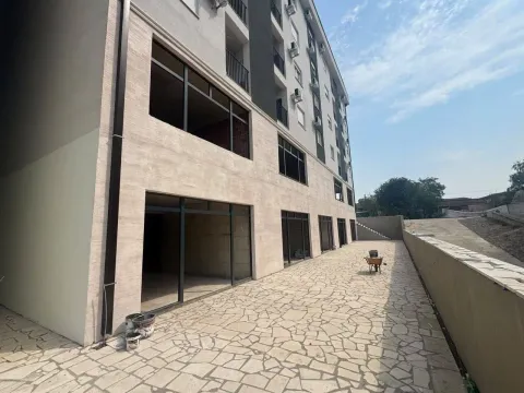 Exterior of an apartment building with a paved courtyard and ground floor commercial spaces. - image 6